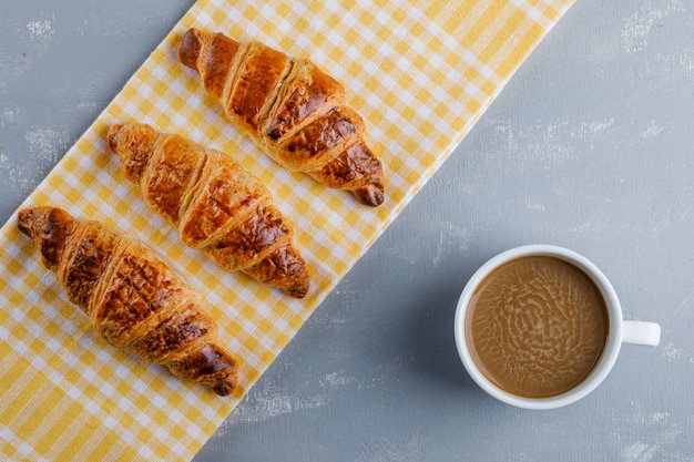 Croissants con café sobre yeso y papel de cocina, plano.