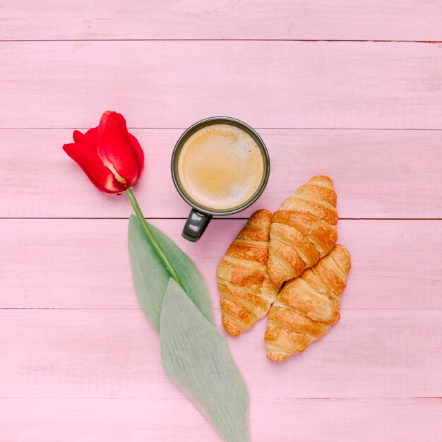 Croissants con café y tulipán en mesa