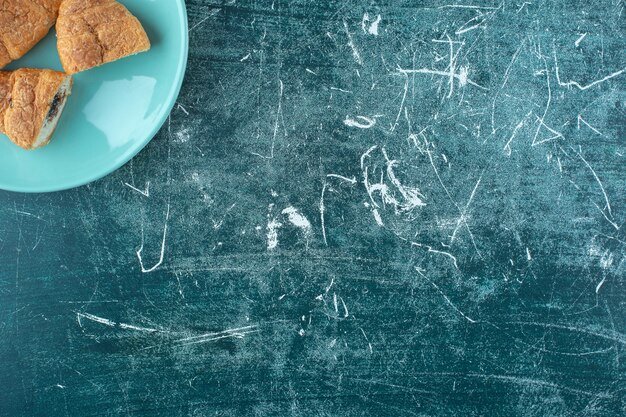 Foto gratuita croissants caseros en un plato, sobre la mesa azul.