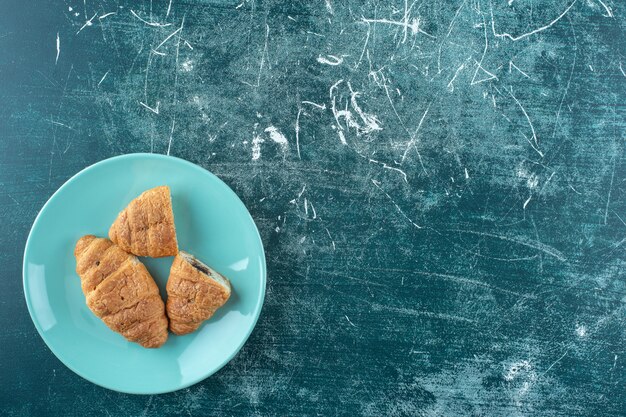 Croissants caseros en un plato, sobre la superficie azul