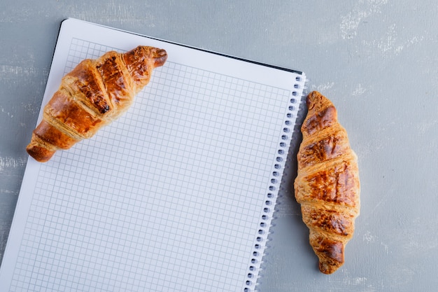 Croissants con cuaderno de espiral, plano.