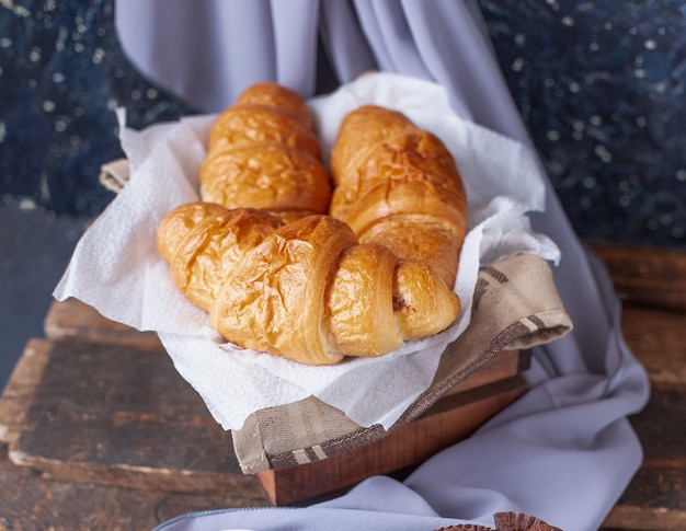 Croissants dentro de una caja de madera sobre un trozo de tejido blanco