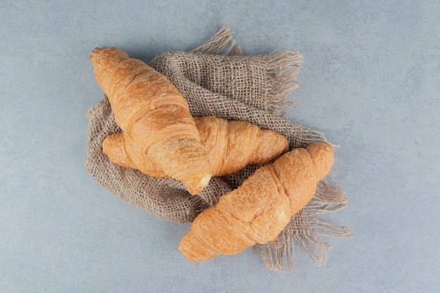 Croissants con dientes sobre una toalla, sobre el fondo de mármol. Foto de alta calidad