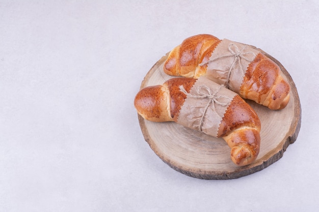 Croissants envueltos con papel en una bandeja de madera