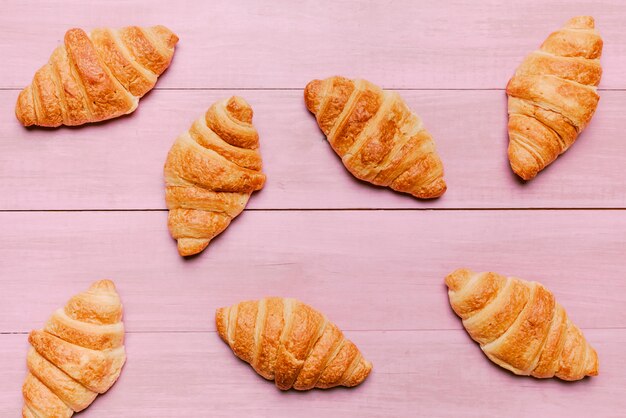 Croissants esparcidos sobre mesa rosa