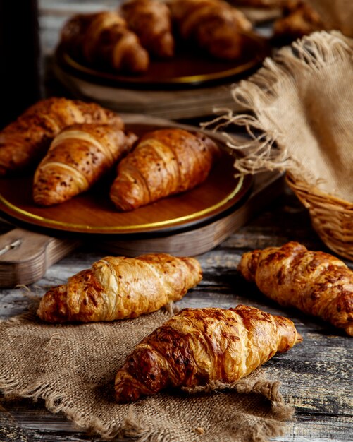 Croissants de mantequilla colocados sobre lino y cestas de paja