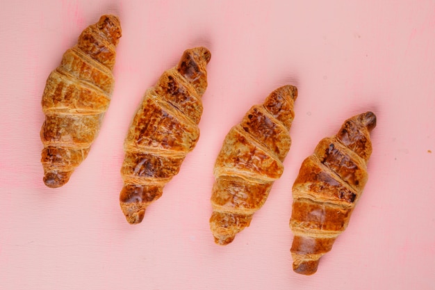 Foto gratuita croissants en una mesa de color rosa. aplanada