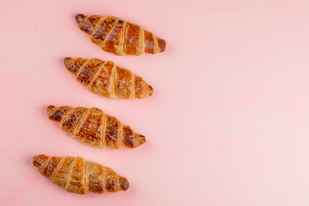 Foto gratuita croissants en una mesa de color rosa. aplanada