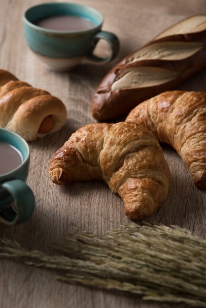 Croissants con pan y taza de café sobre fondo de madera