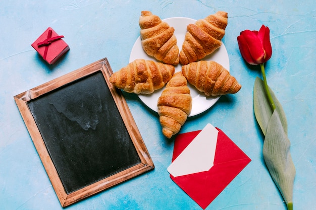 Foto gratuita croissants en placa con pizarra en blanco