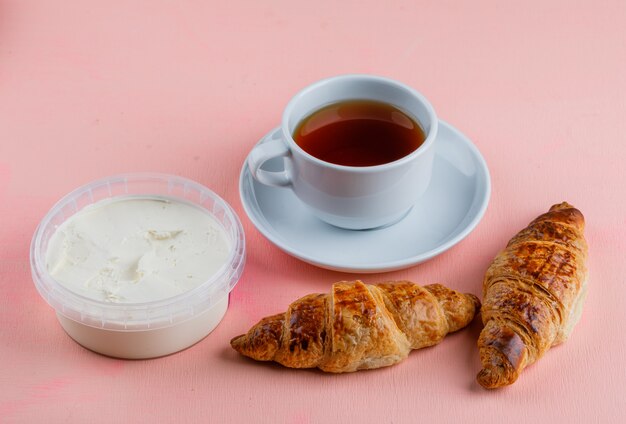 Croissants con queso crema, té en mesa rosa,