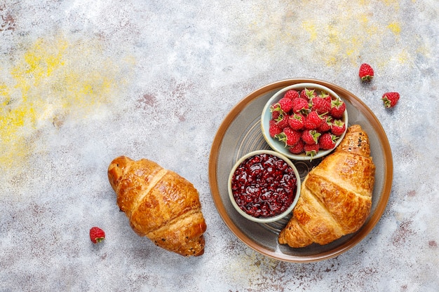 Croissants recién horneados con mermelada de frambuesa y frutas de frambuesa.