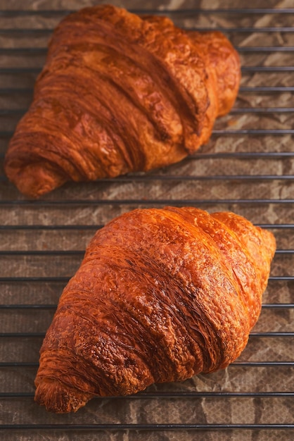 Croissants recién horneados en una rejilla de enfriamiento Primer plano de tiro vertical y enfoque selectivo en un croissant Pastelería fresca para el desayuno francés