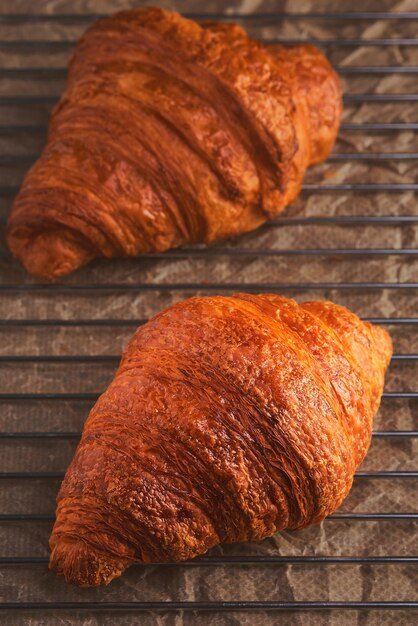 Croissants recién horneados en una rejilla de enfriamiento Primer plano de tiro vertical y enfoque selectivo en un croissant Pastelería fresca para el desayuno francés