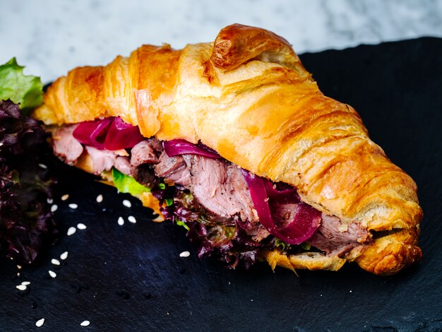 Croissants rellenos de carne en rodajas y hierbas.