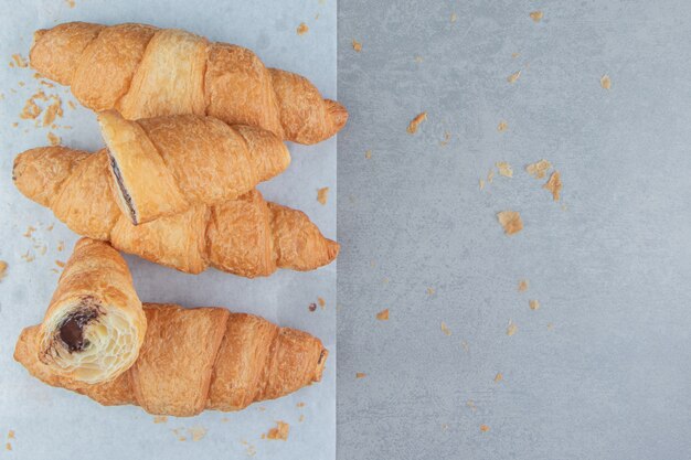 Croissants en rodajas sobre pape, r sobre el fondo de mármol. Foto de alta calidad