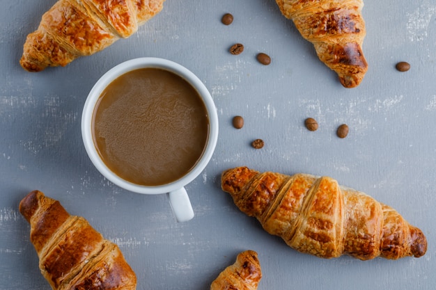 Croissants con una taza de café, granos de café, plano.