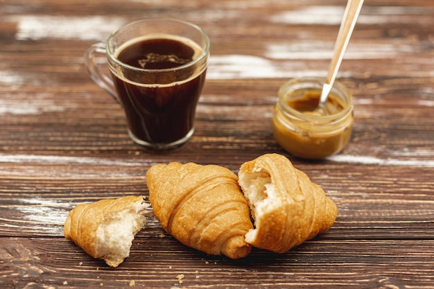 Foto gratuita croissants con taza de café y mantequilla de maní sobre la mesa