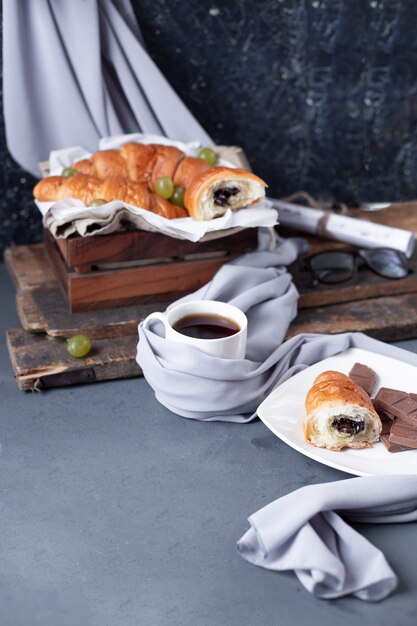 Croissants con una taza de espresso en la mesa azul