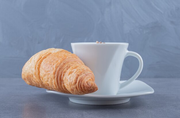 Croissants con taza de té. sobre fondo gris.