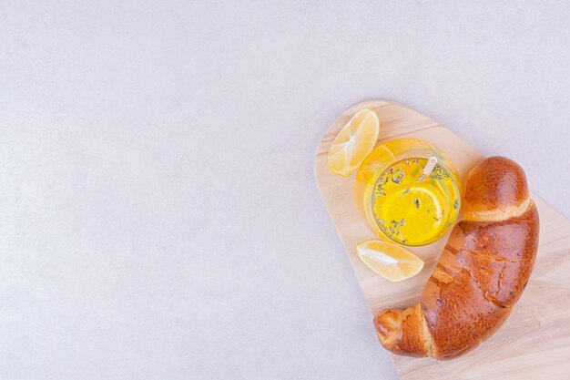 Croissants con un vaso de limonada sobre superficie blanca