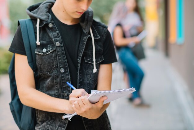 Crop estudiante con bloc de notas en la calle
