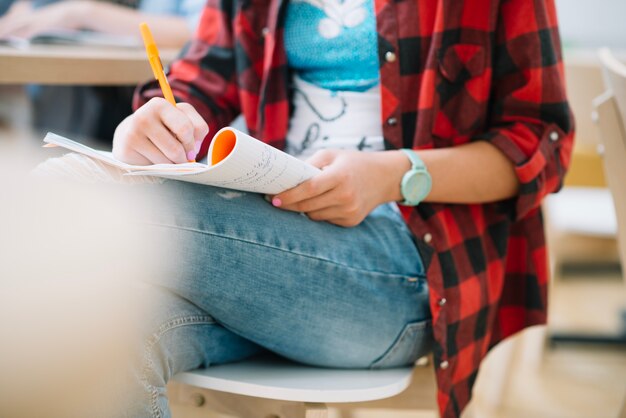 Crop estudiante escribiendo en copybook