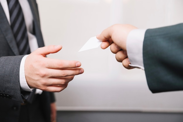 Crop man giving business card to partner