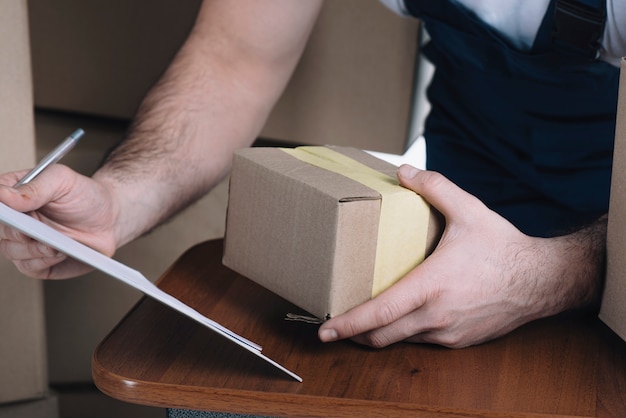 Foto gratuita cropier mensajero con caja de cartón y portapapeles