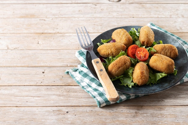 Croquetas fritas tradicionales españolas sobre mesa de madera