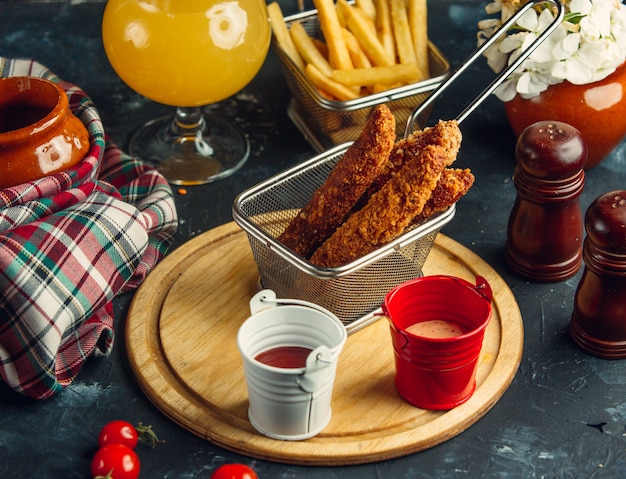 croquetas de pollo servidas con papas fritas, mayonesa y ketchup