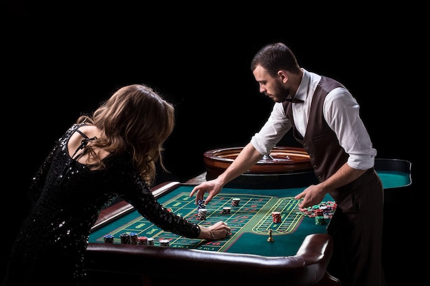 Croupier y jugadora en una mesa en un casino. Imagen de una rueda de ruleta de casino clásica. Juego. Casino. Ruleta. Póker