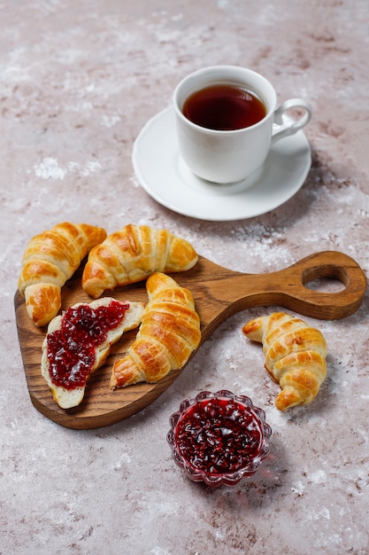 Cruasanes caseros sabrosos frescos con mermelada de frambuesa en blanco grisáceo. Pastelería francesa