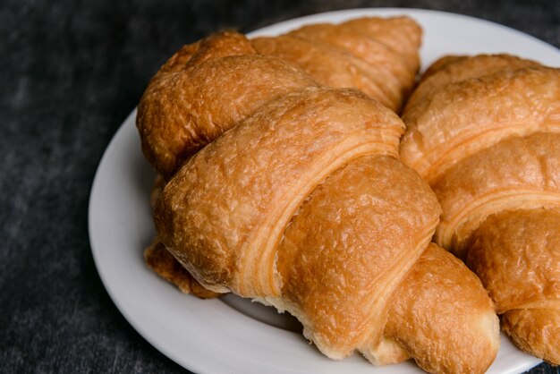 cruasanes en plato redondo blanco y pared de mesa gris