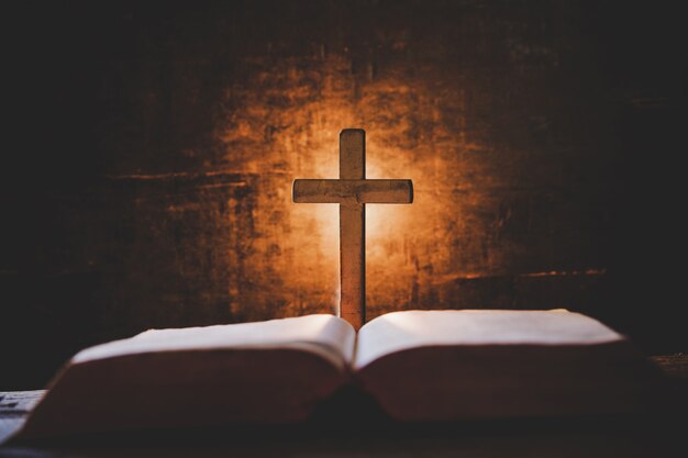 Cruce con la biblia y la vela en una vieja mesa de madera de roble.