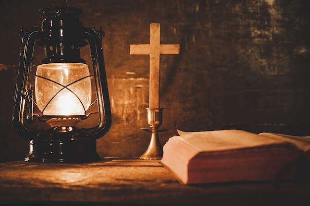 Cruce con la biblia y la vela en una vieja mesa de madera de roble.