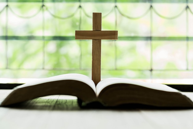 Foto gratuita cruces que se abren sobre la biblia en una mesa de madera.