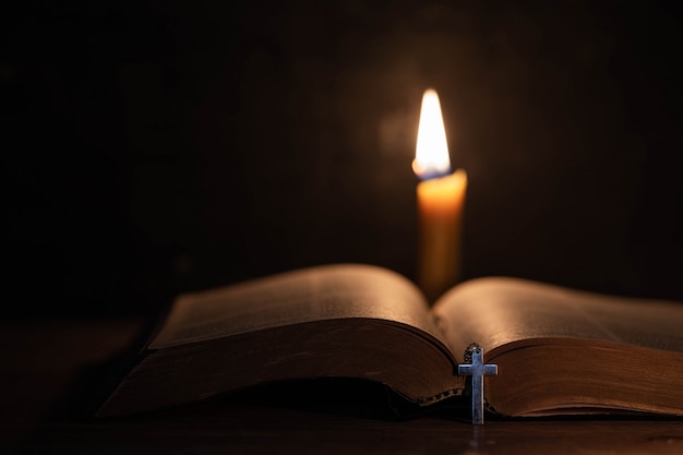 Cruz con biblia y vela sobre una vieja mesa de madera de roble.