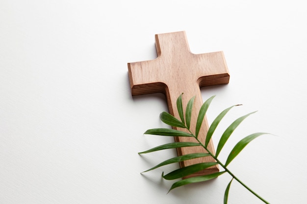 Cruz de madera de alto ángulo y hoja verde.