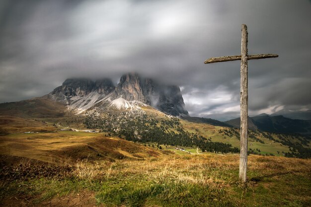 Cruz de madera en la colina cubierta de vegetación con los Dolomitas en Tirol del Sur