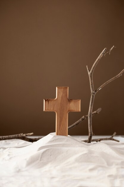 Cruz de madera y ramas sobre arena.