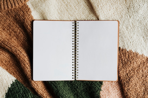 Cuaderno abierto en blanco sobre un suéter