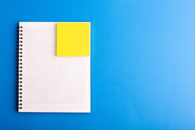 Cuaderno abierto de vista frontal con adhesivo en la superficie azul