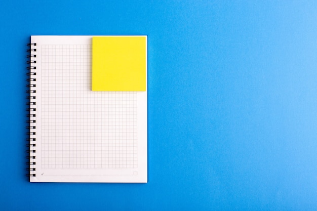 Cuaderno abierto de vista frontal con adhesivo en la superficie azul