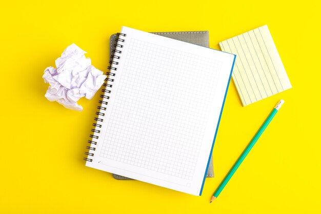 Cuaderno abierto de vista superior con lápiz sobre superficie amarilla