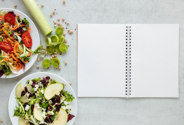 Cuaderno al lado del plato con ensalada