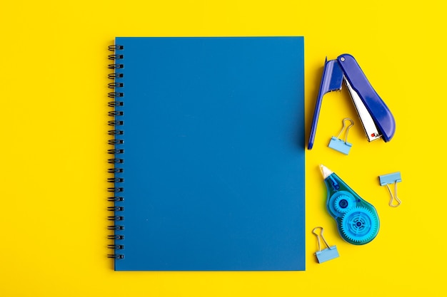 Foto gratuita cuaderno azul abierto de vista frontal con pegatinas en superficie amarilla