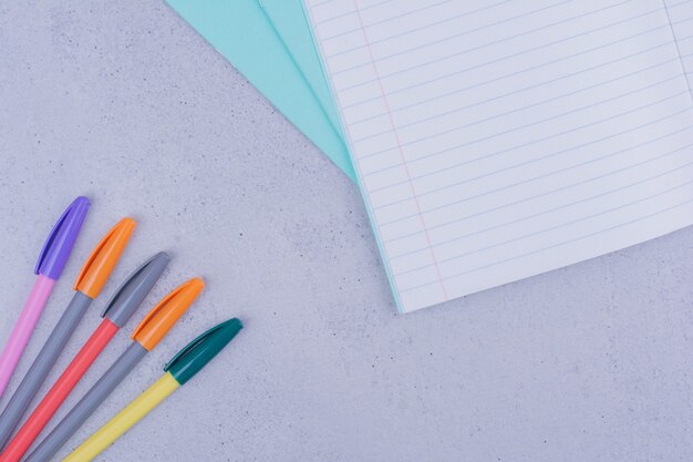 Cuaderno en blanco blanco con bolígrafos en gris.