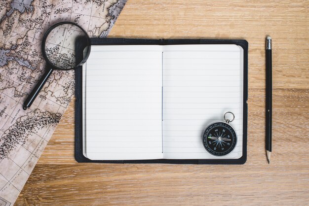 Cuaderno en blanco con brújula y otras herramientas de viaje