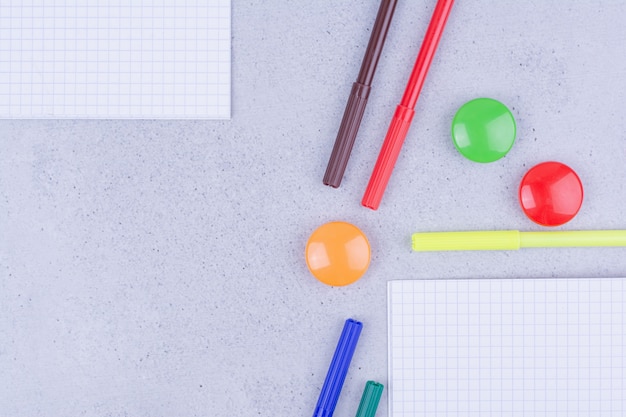 Un cuaderno en blanco con lápices de colores alrededor de la superficie gris